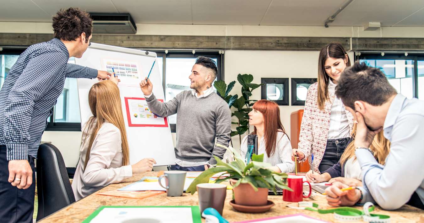 pessoas reunidas em mesa  com flip chart