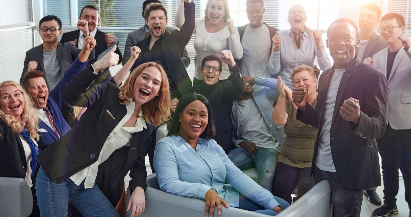 Equipe feliz com diversos funcionários corporativos no lobby de um escritório.