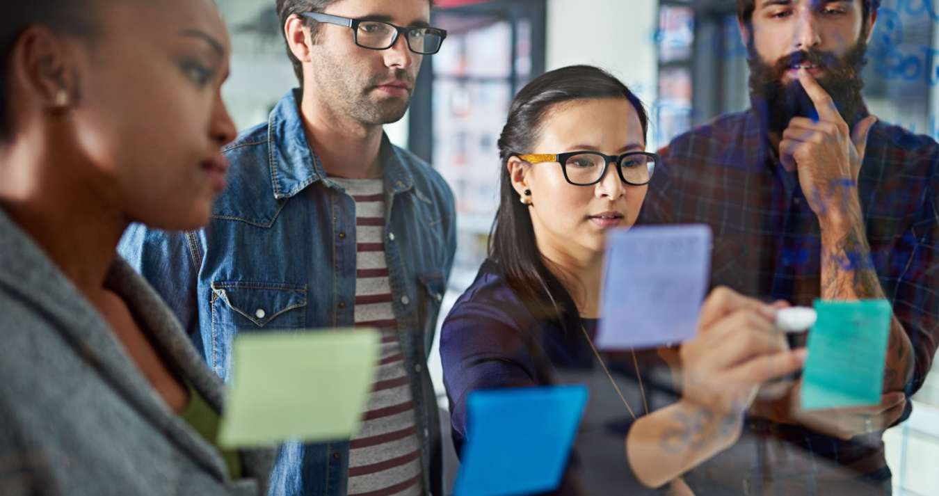 Pessoas reunidas realizando planejamento com postit