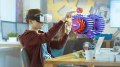 Uma criança utilizando um óculos de realidade virtual tentando pegar objetos fictícios