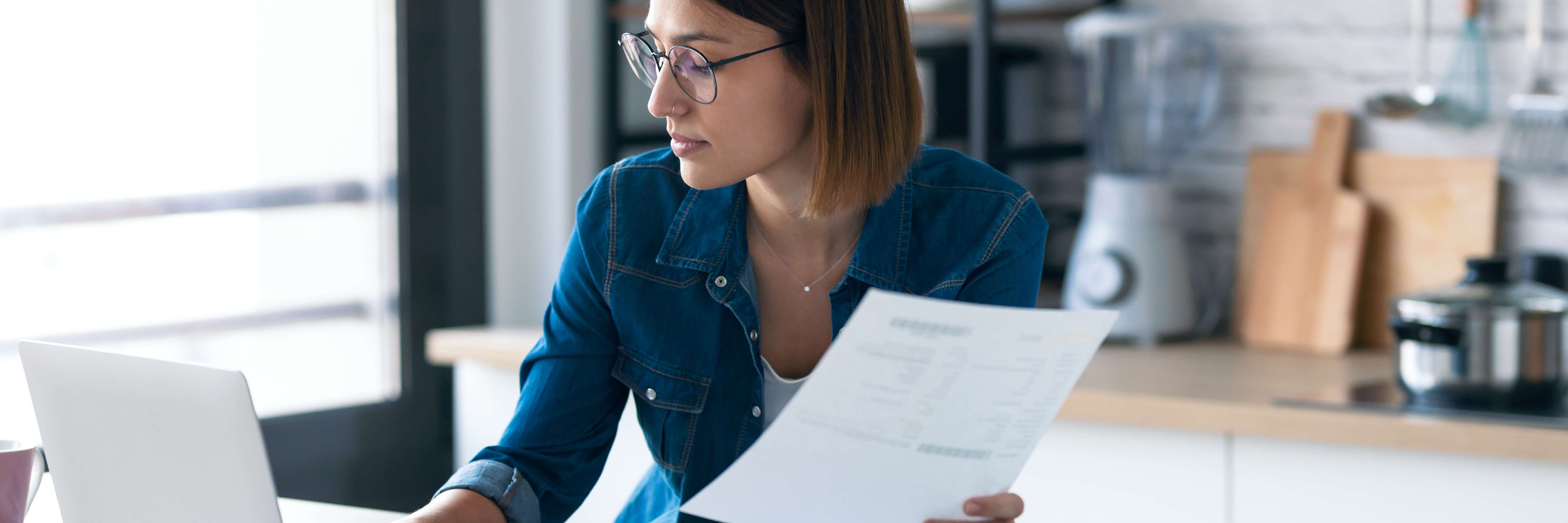 Mulher concentrada usando notebook e avaliando conta financeira