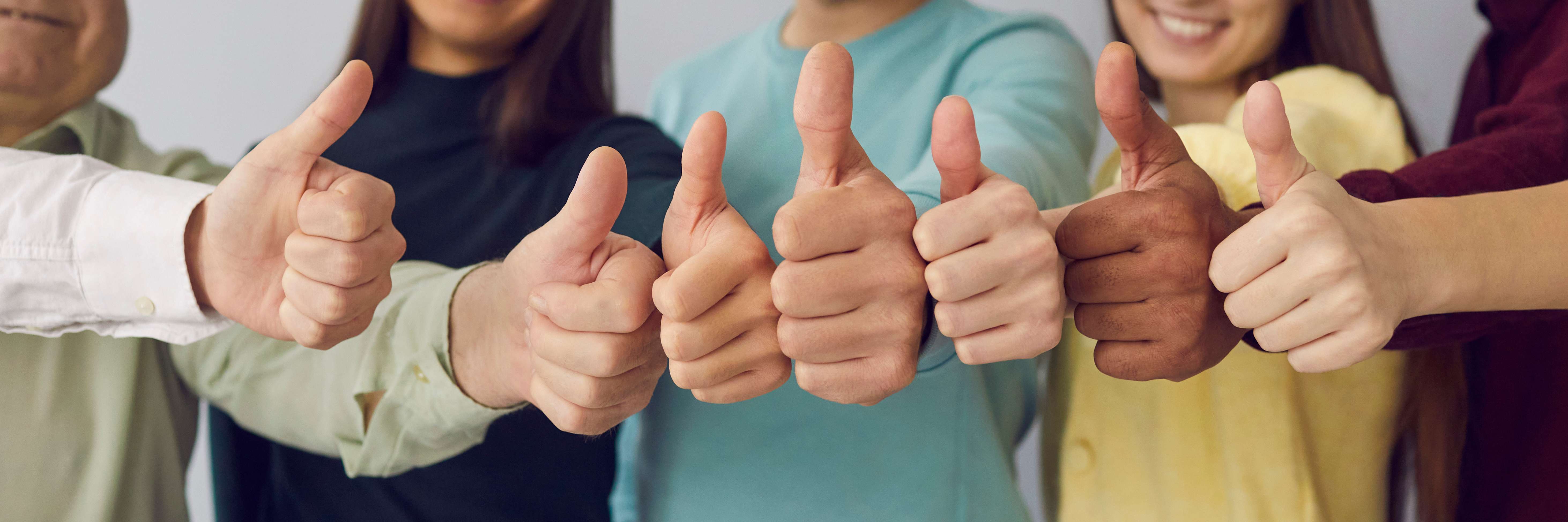 Pessoas lado a lado, fazendo sinal de positivo com as mãos.